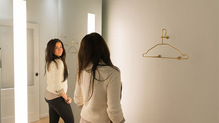 Клієнтка SuperTrash розглядає себе в дзеркалі AmbiScene від Philips з увімкненим налаштуванням ’Денне освітлення’
