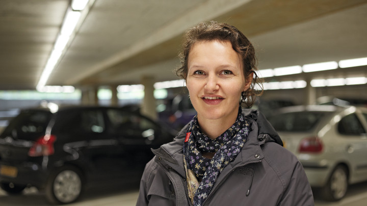  Усміхнена жінка на фоні транспорту на автостоянці Eiteren, освітленій обладнанням Philips 