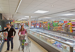 Мужчина и женщина идут по проходу супермаркета, освещенного энергосберегающими световыми решениями от Philips 