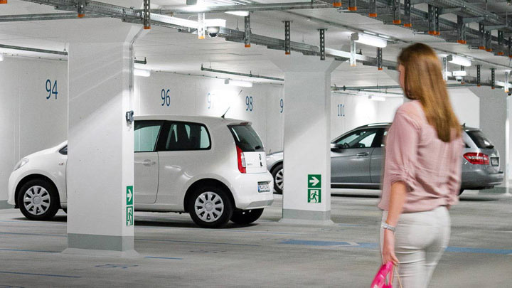 Женщина подходит к автомобилю на хорошо освещенной подземной парковке 